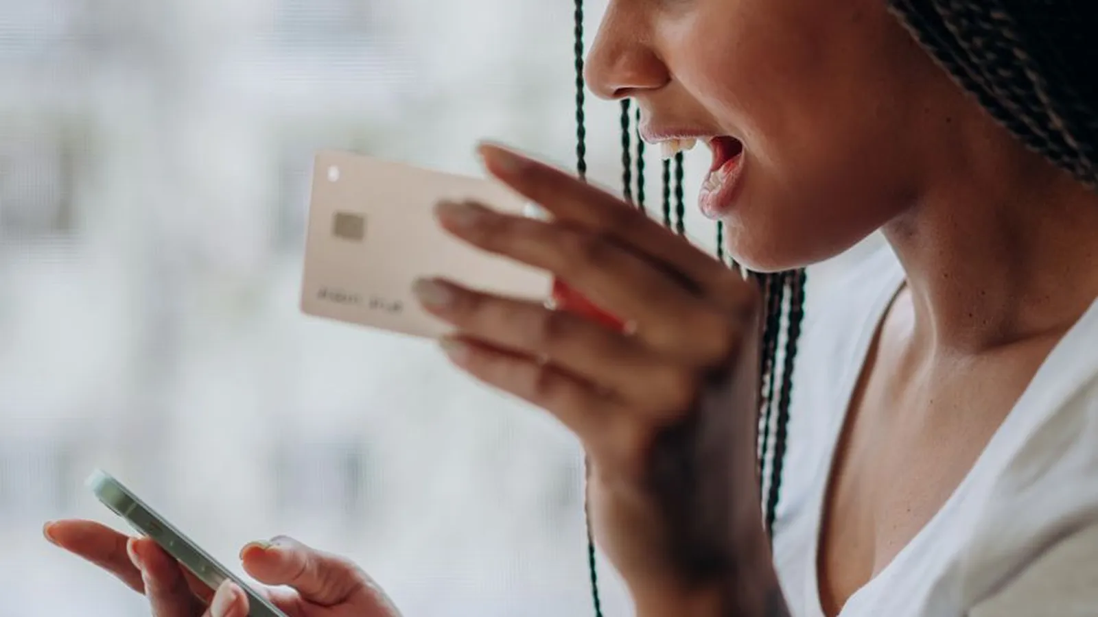 A woman checking a mobile phone payment confirmation, representing the moment a fake mobile money screenshot needs verifying