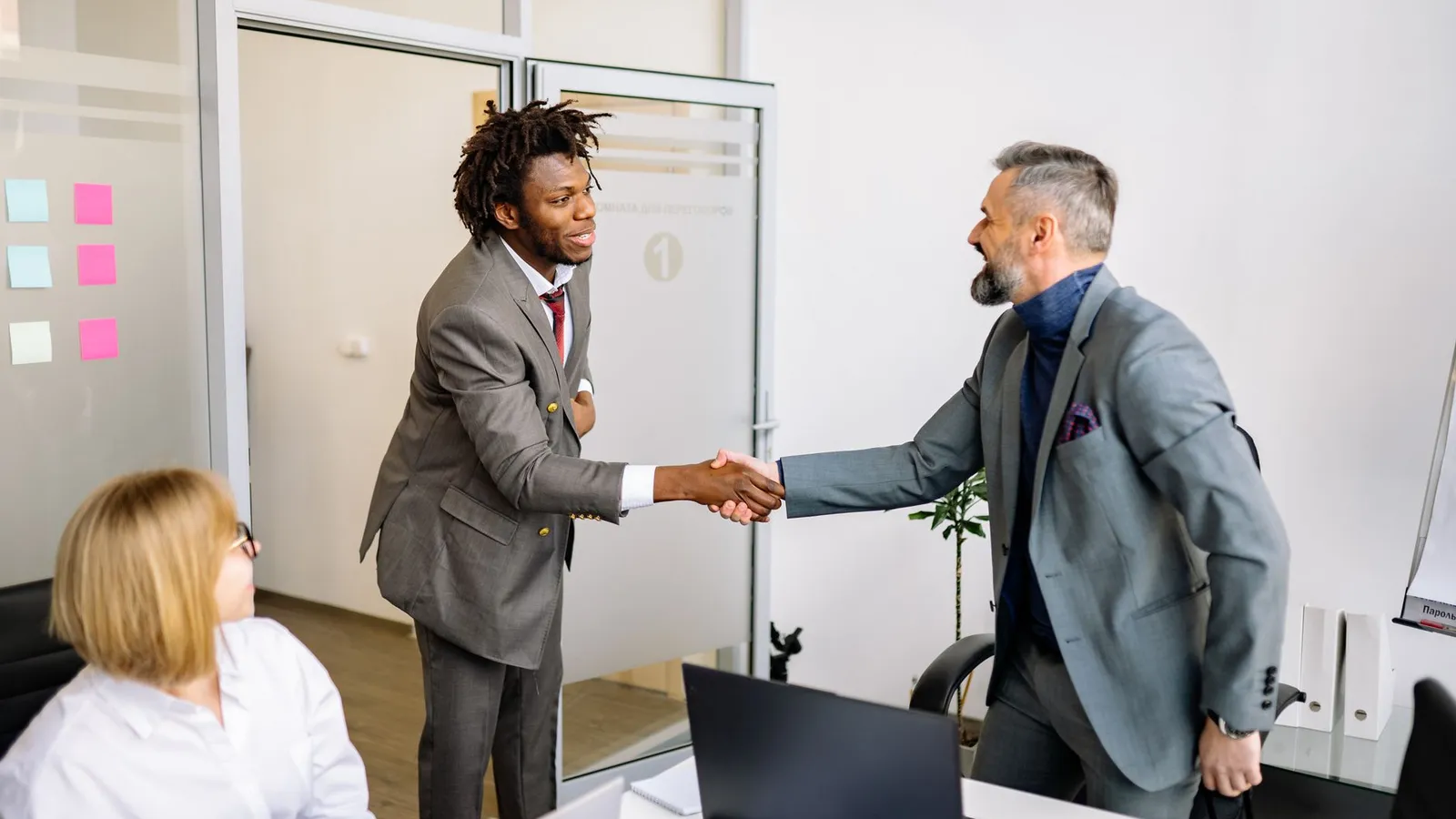 Two businessmen shaking hands in an office, representing a vendor relationship that can hide a kickback arrangement