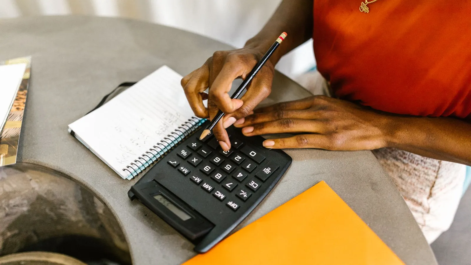 Hands using a calculator beside a notebook, representing working out a rough, flexible budget range before the first conversation