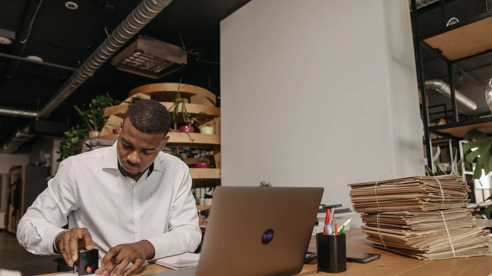 A man reviewing paperwork and a laptop surrounded by stacked documents, representing gathering existing facts and records before the first call