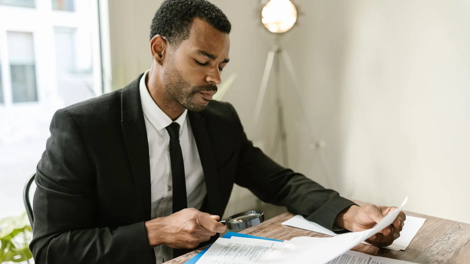 An investigator examining a financial document with a magnifying glass, representing the fraud and financial irregularity investigation work at the core of corporate investigation