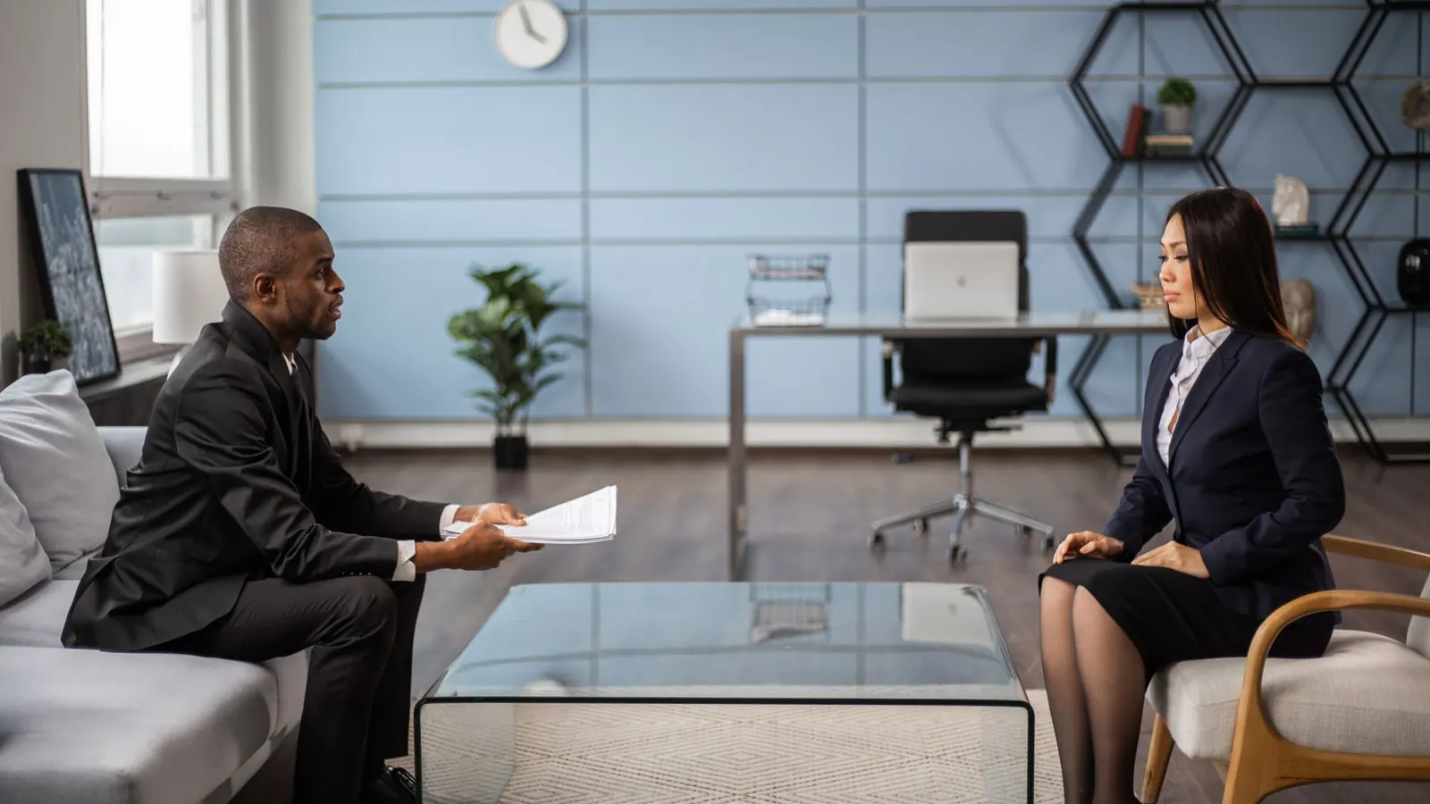 An executive candidate handing over documents during an interview in an office, representing background verification for a senior hire