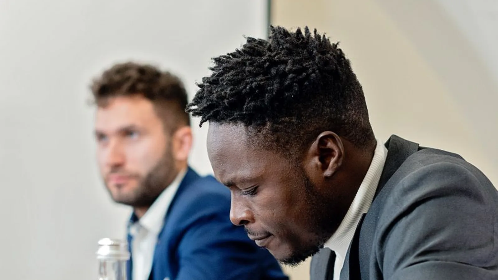 An African businessman reviewing documents in a boardroom meeting alongside an international colleague