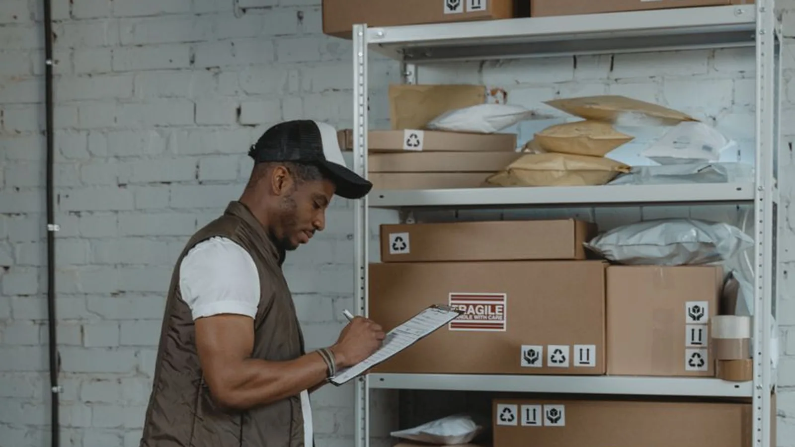 A man with a clipboard inspecting shelves of inventory in a warehouse, representing an independent site visit to verify claimed assets