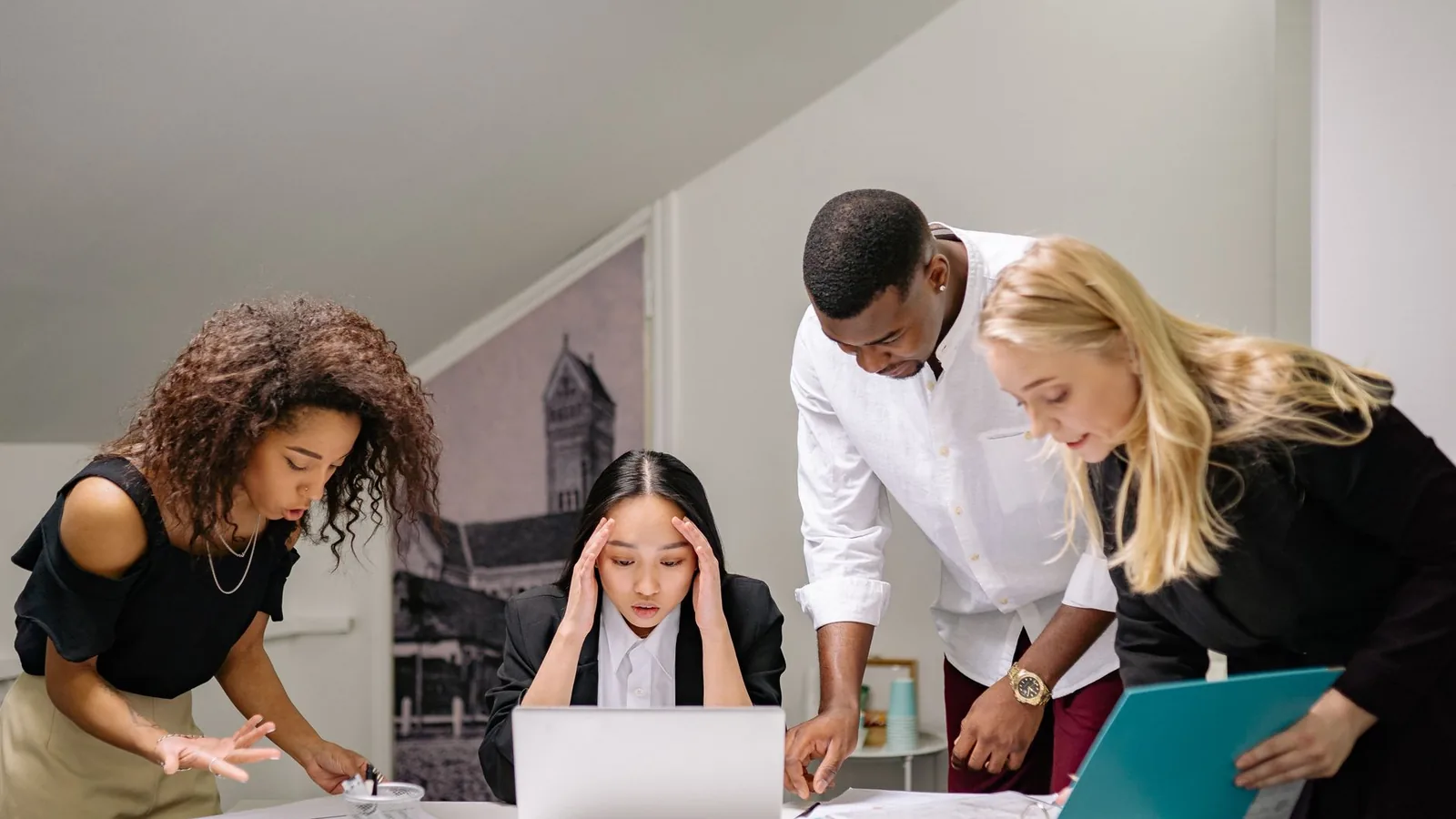 A team of colleagues gathered around a laptop working urgently together, representing an investigation running in parallel with a fast-moving deal timeline
