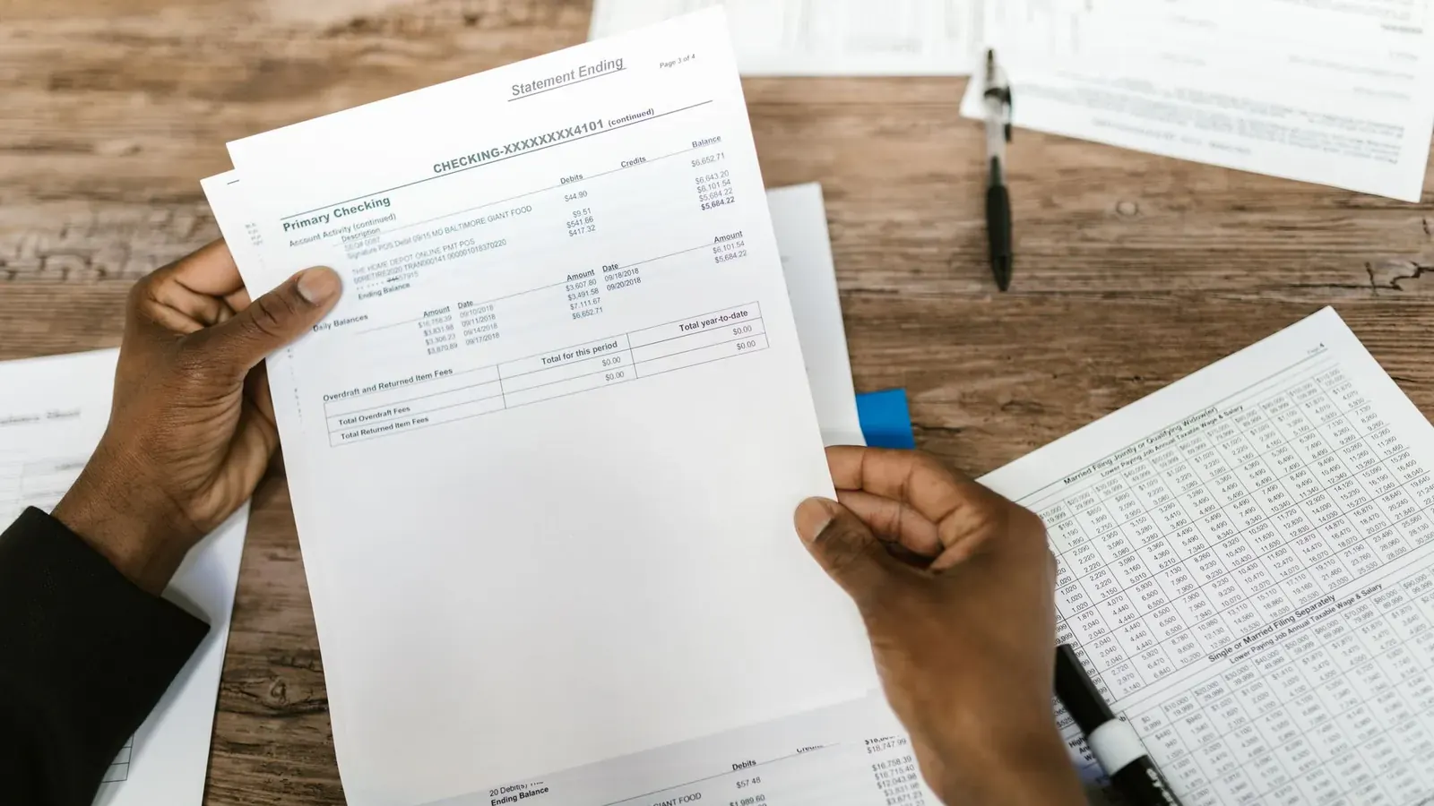 Two colleagues reviewing a bank statement together at a wooden desk, representing the reconciliation work at the center of fraud detection