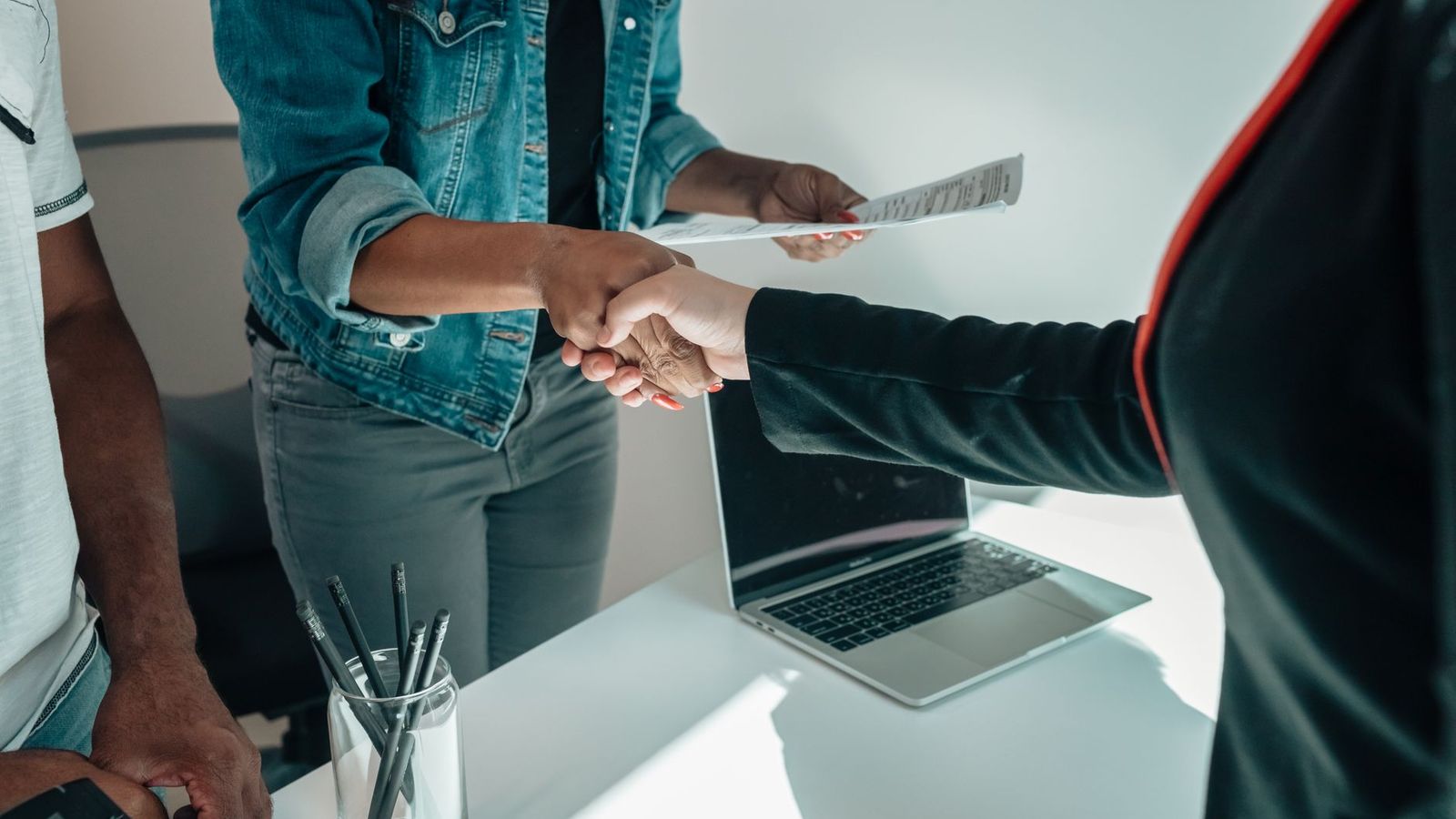 Job candidate shaking hands and exchanging paperwork during a background check interview