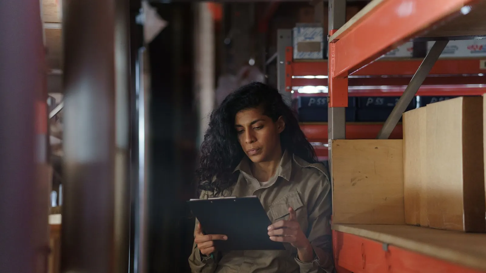 A warehouse worker reviewing a clipboard against stock on the shelves, representing the walkthrough of money and stock flows at the center of a fraud risk assessment