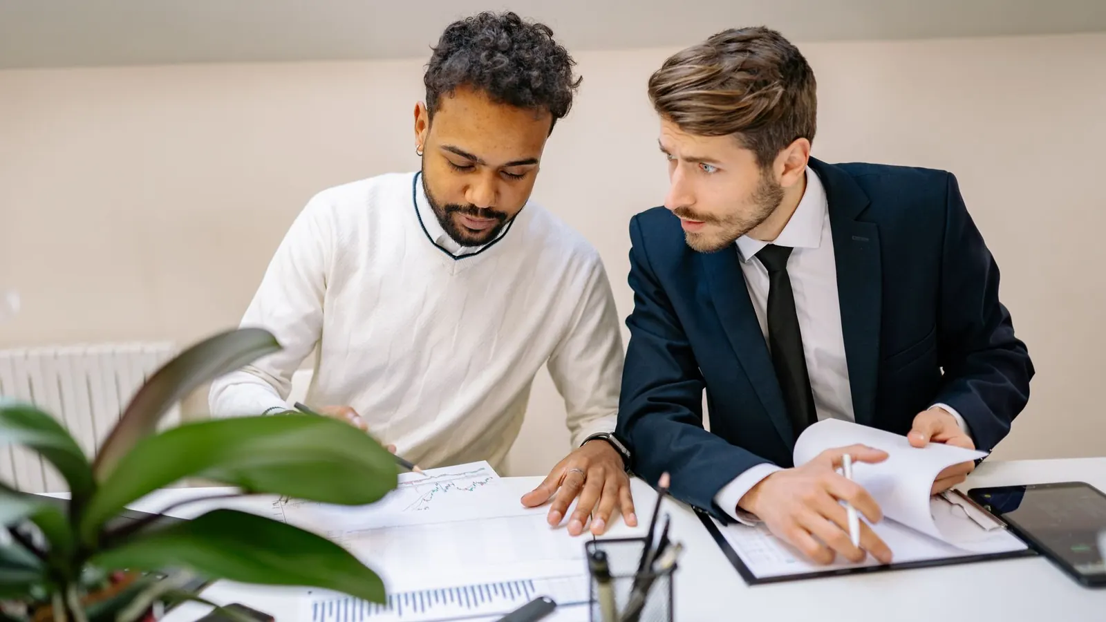 Two colleagues closely reviewing a financial chart together at a desk, representing the scrutiny at the center of fraud risk management