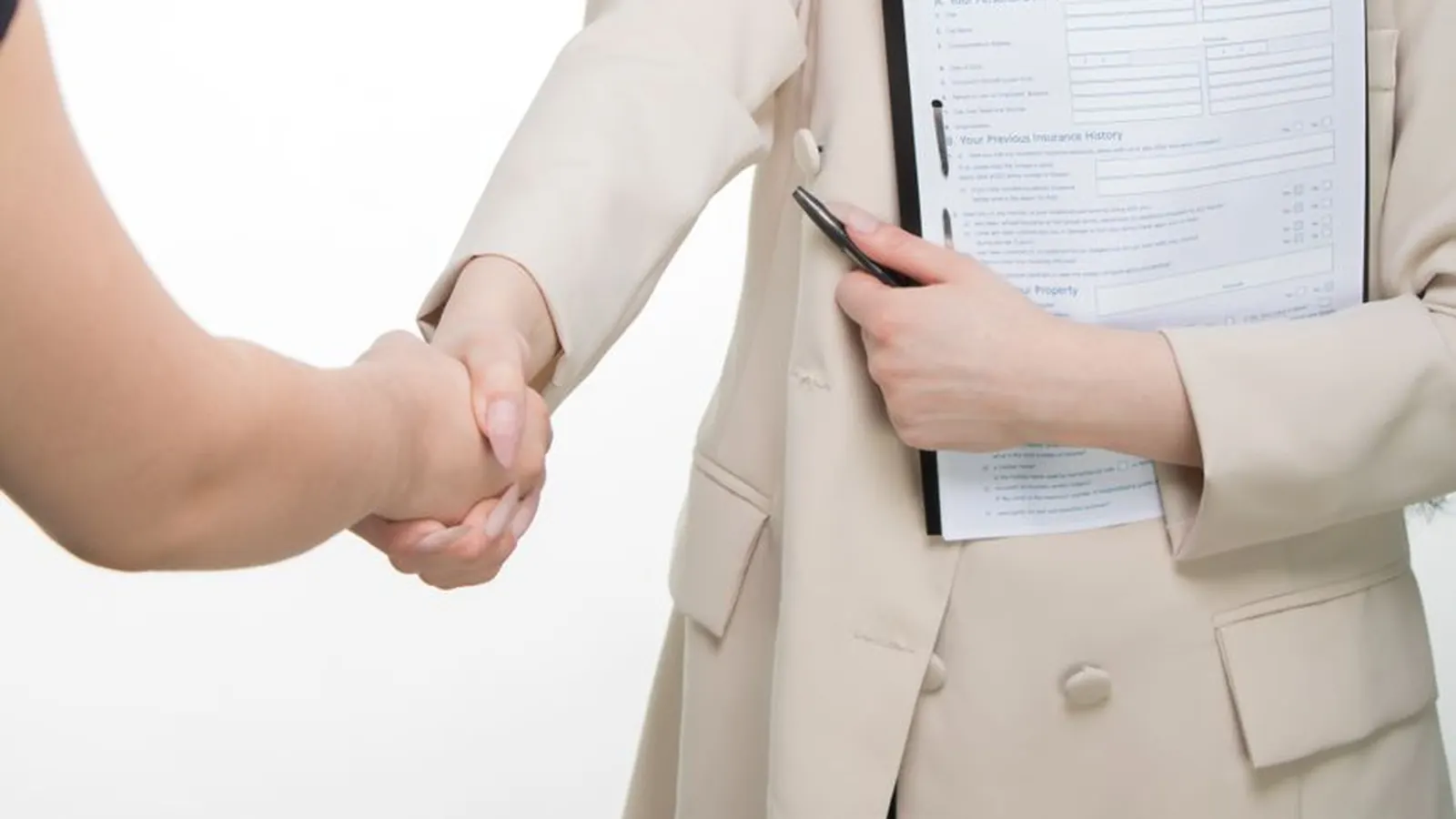 Two people shaking hands over a home insurance policy document on a clipboard, representing fidelity and crime insurance as a backstop for fraud risk
