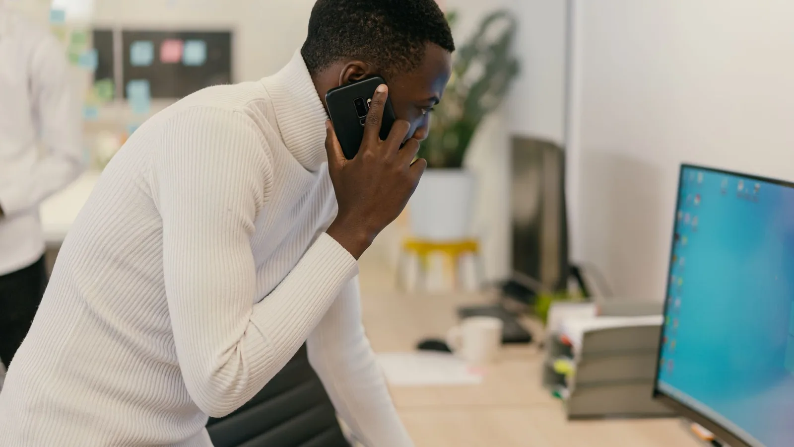 A man leaning over his desk on a tense phone call, representing the communication and time zone barriers of investigating from abroad