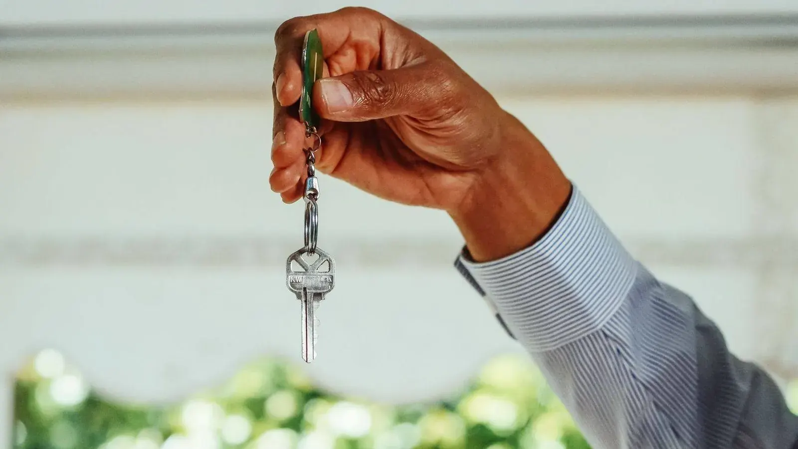 Hand holding a set of house keys, representing property and asset tracing for debt recovery