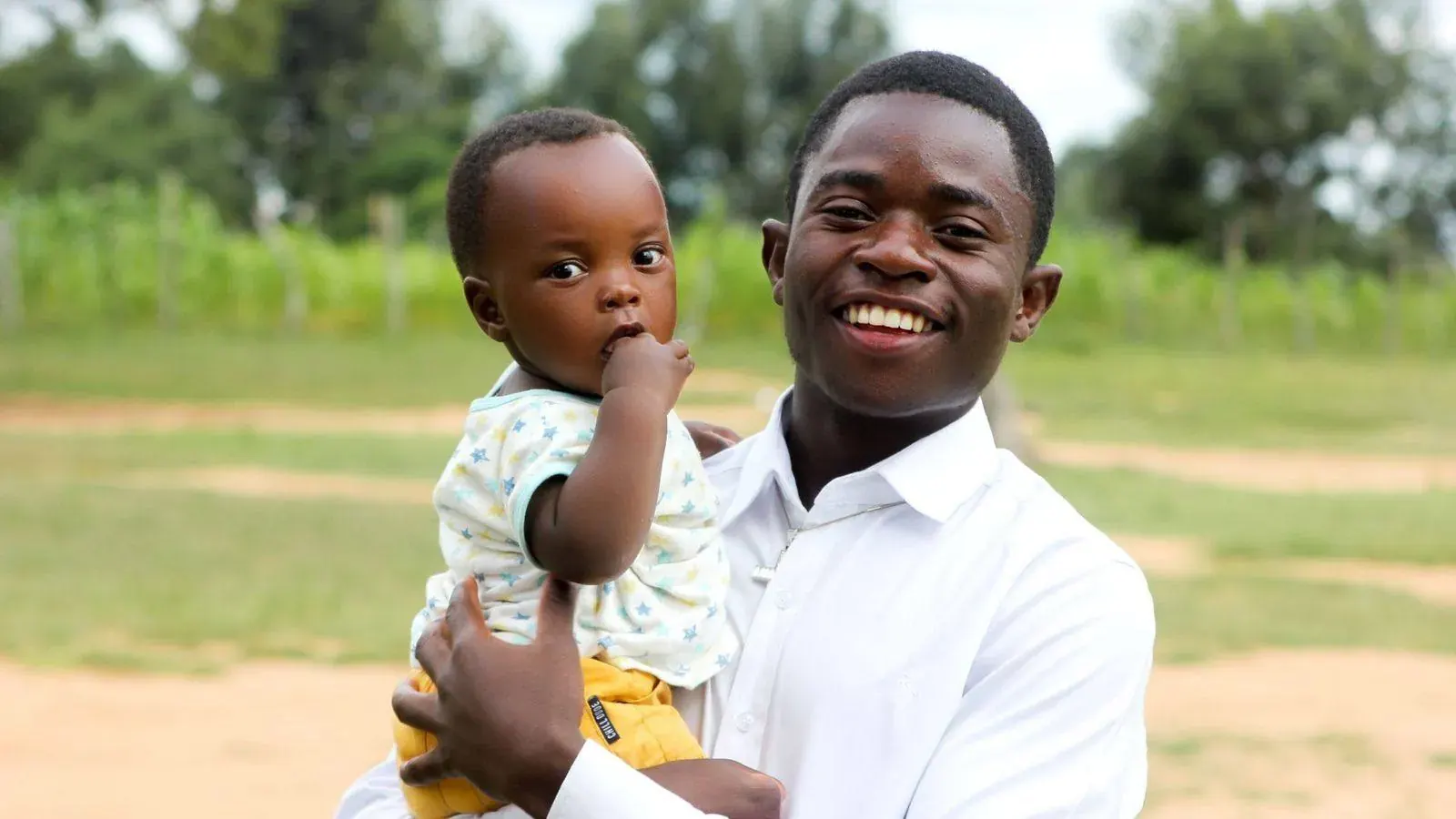 A father holding his young child outdoors in Tanzania