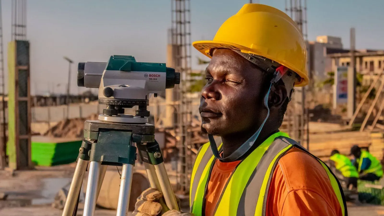 Land surveyor using measuring equipment at a construction site in Tanzania