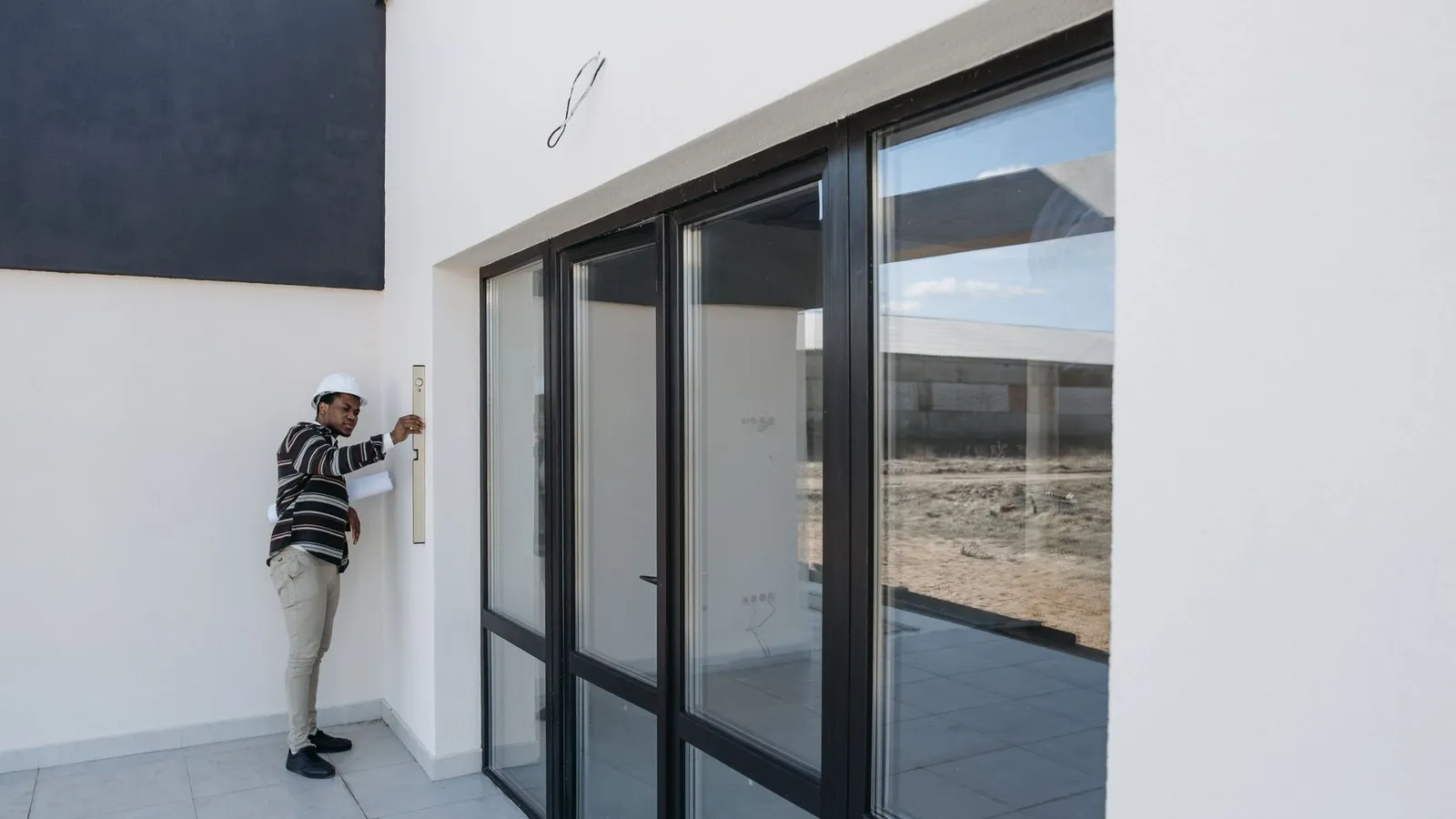 A man inspecting the exterior of a property with glass doors, representing the on-site verification that supports what a policyholder has reported
