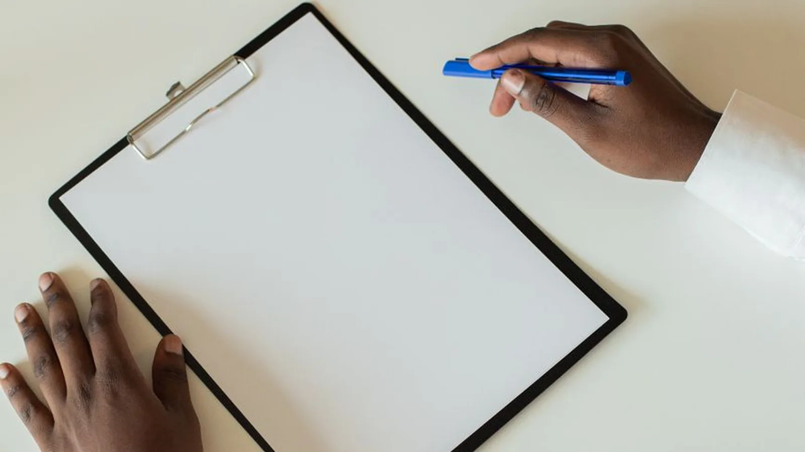 A person's hands resting on a blank clipboard with a pen, representing the short verification checklist worth running before hiring a firm