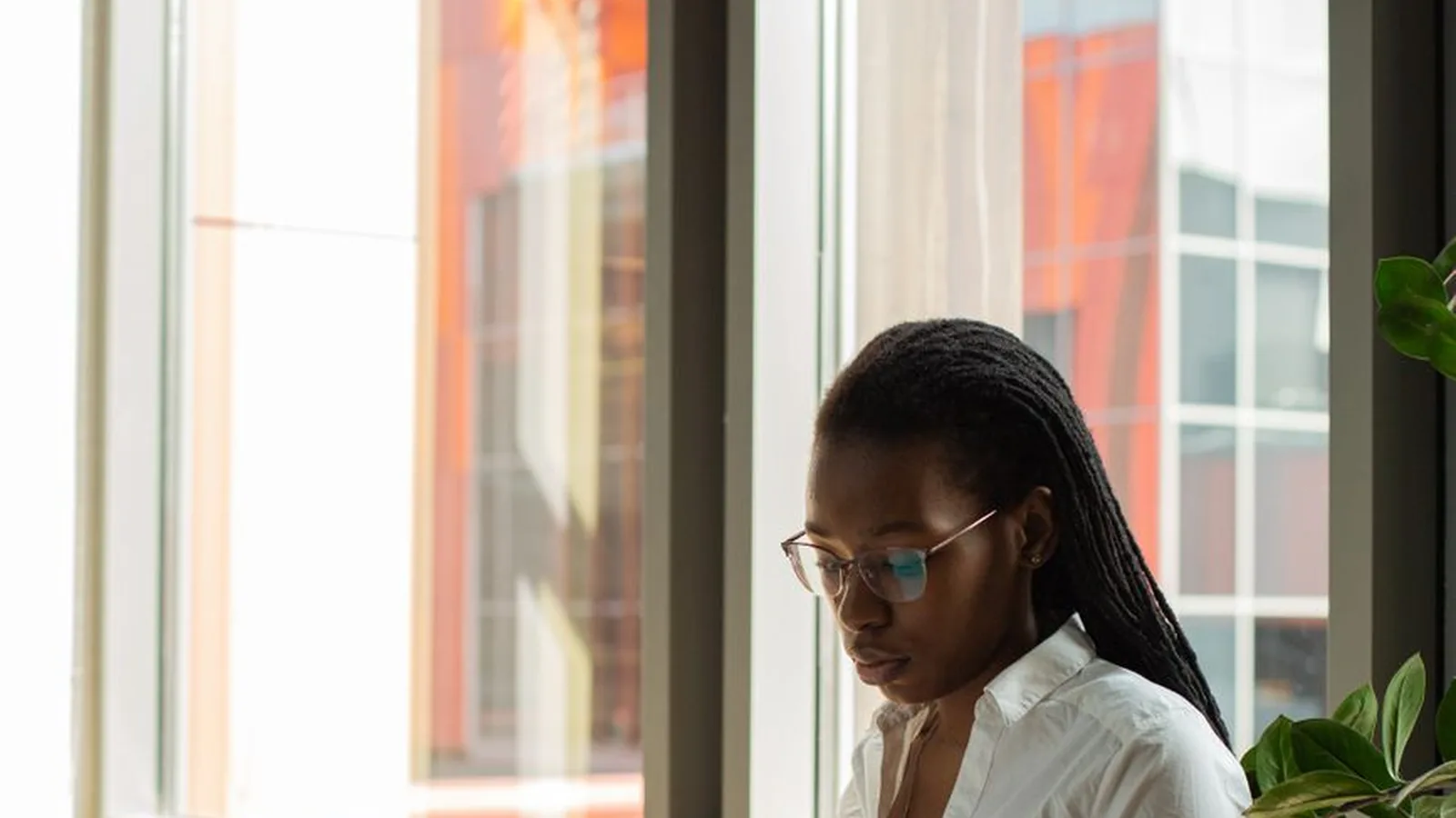 A woman by an office window reviewing a document, representing the regulatory framework private investigators in Tanzania fall under