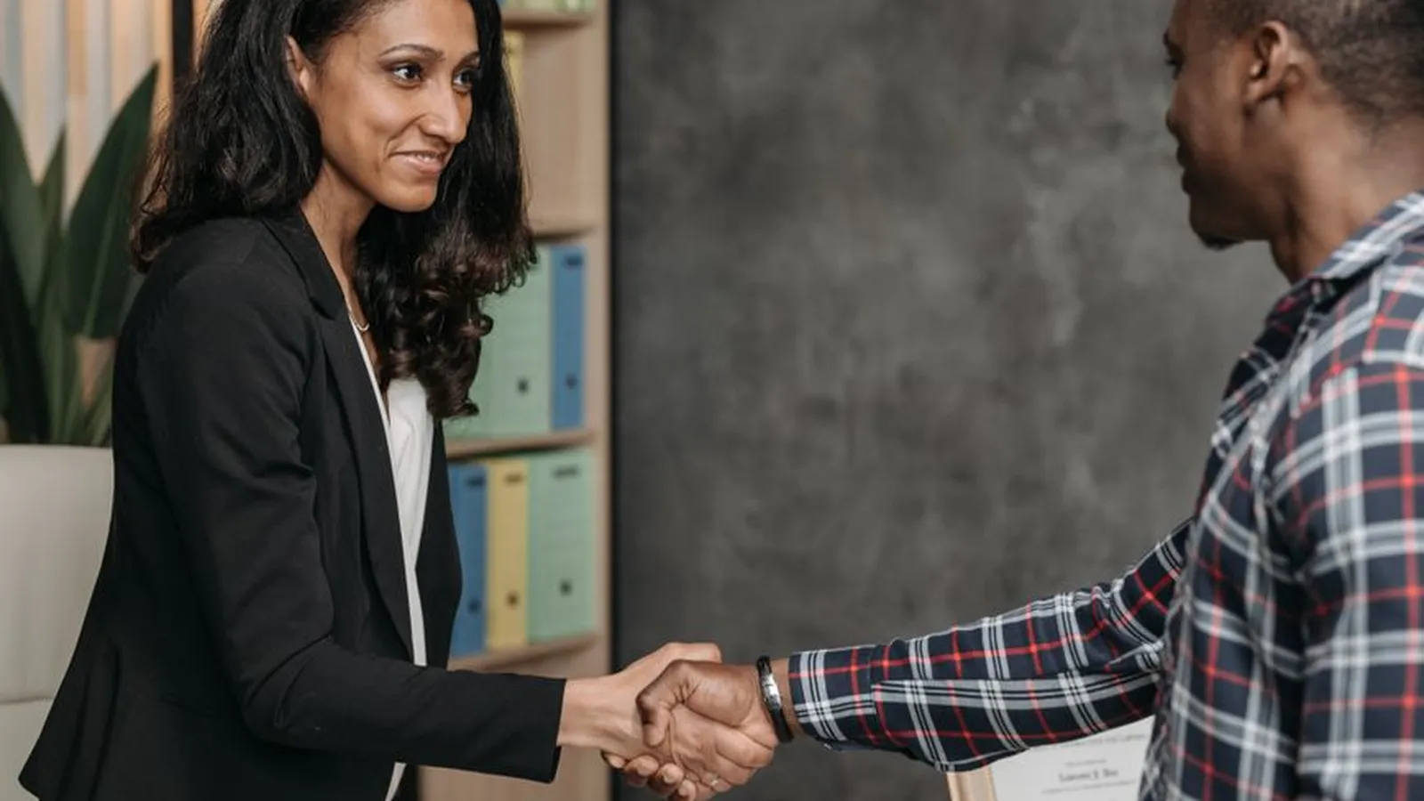 A businesswoman shaking hands with a client during an office consultation, representing the initial conversation where investigation costs get scoped to the case
