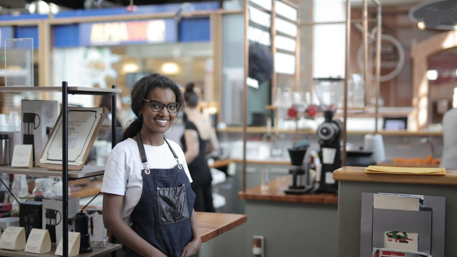 A confident small business owner in an apron standing in her shop, representing verifying a franchise or licensing partner