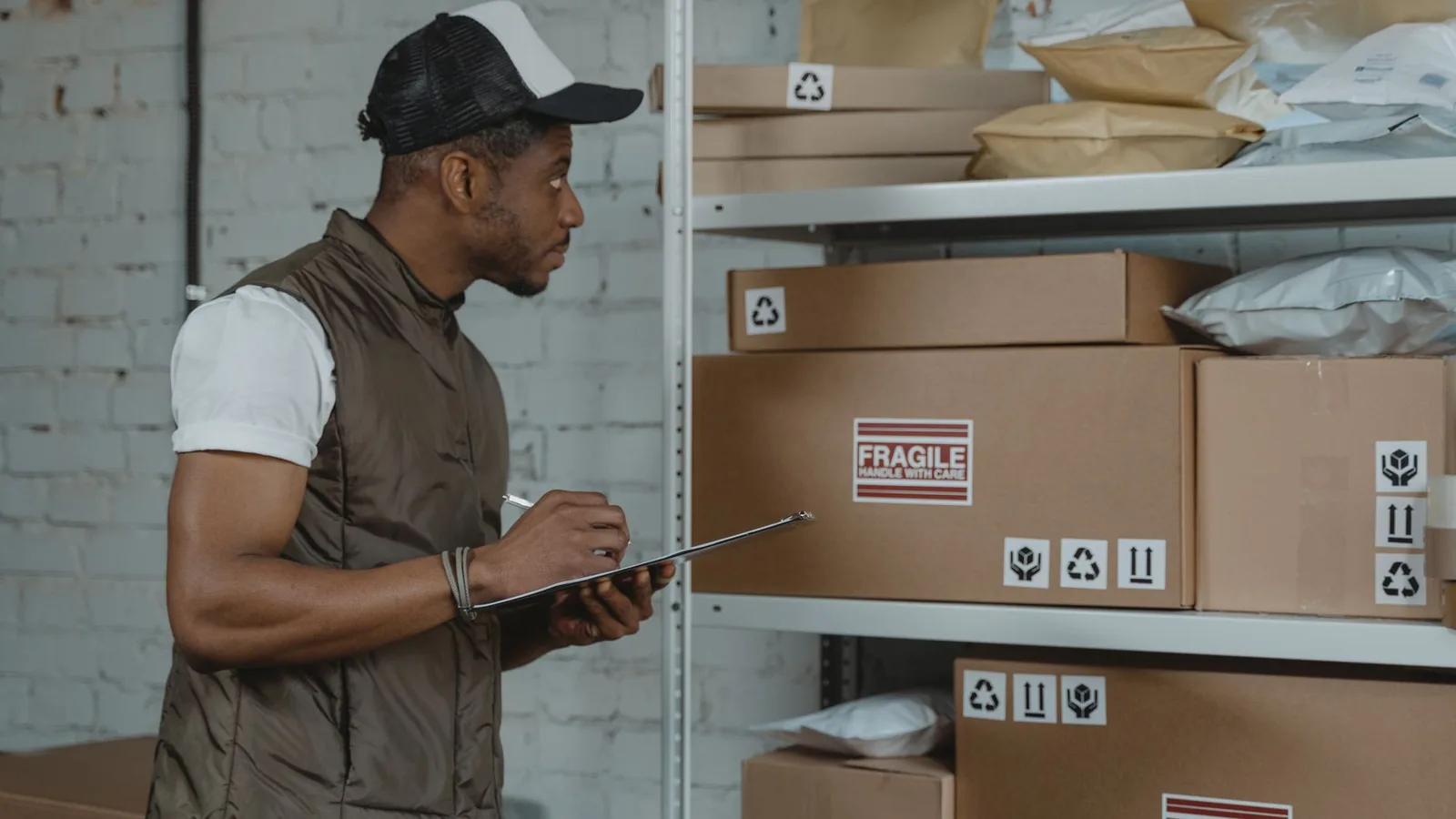 A man with a clipboard inspecting boxes on a warehouse shelf, representing verifying a new supplier before extending credit
