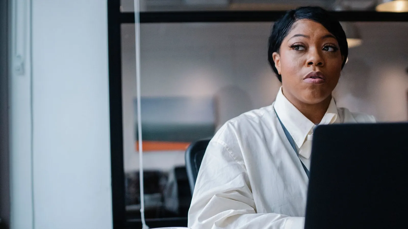 A businesswoman working on a laptop in a modern office, representing the professional, procedural image the word investigator carries