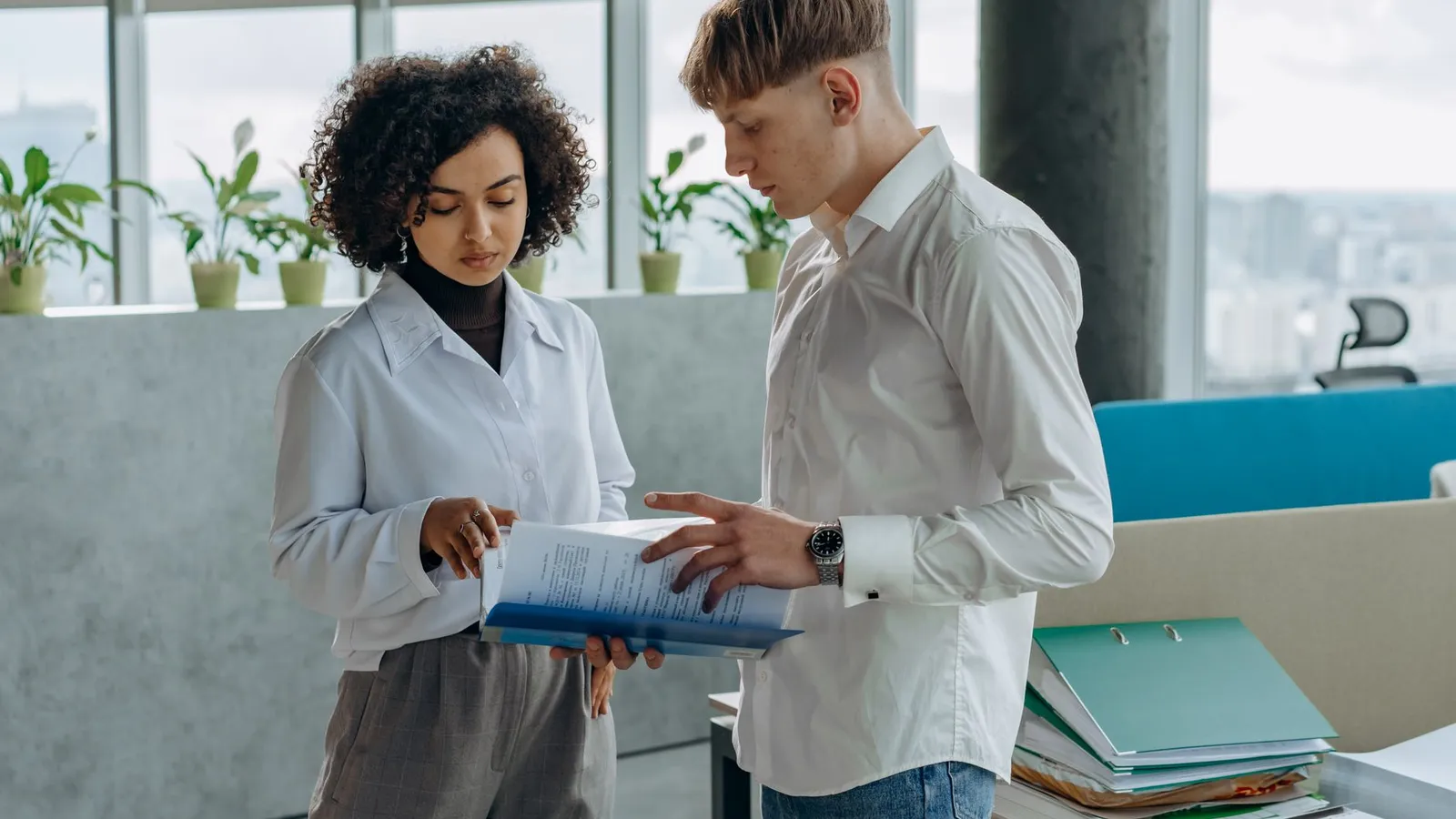 Two colleagues reviewing a folder of documents together in an office, representing the shared work behind either title