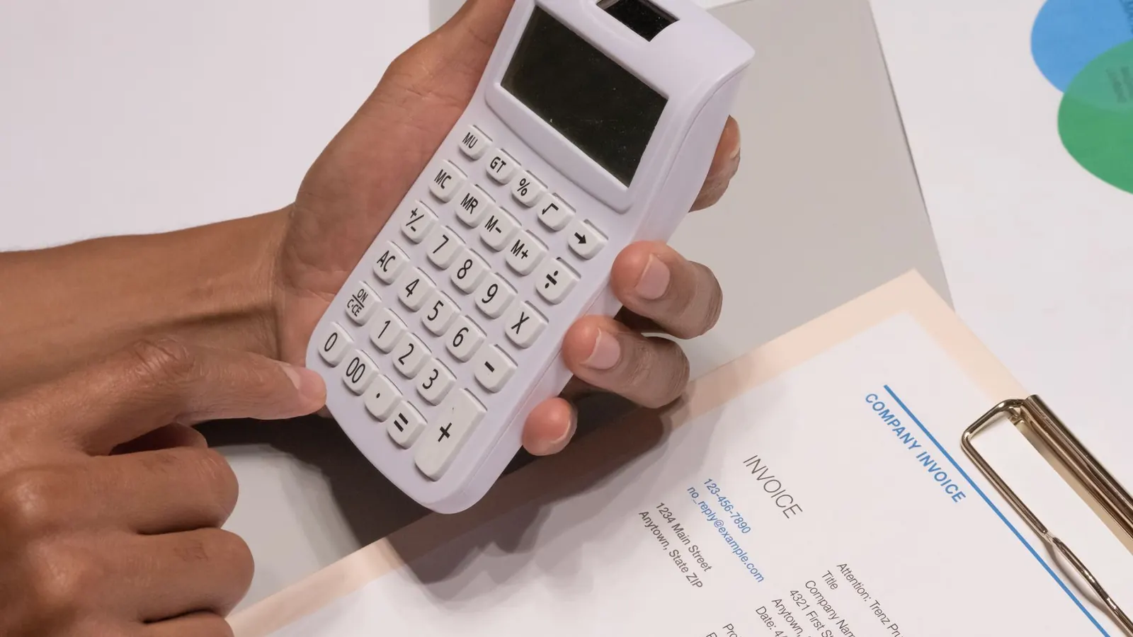 A hand holding a calculator next to an invoice document with a pen, representing the cost factors behind a private investigation