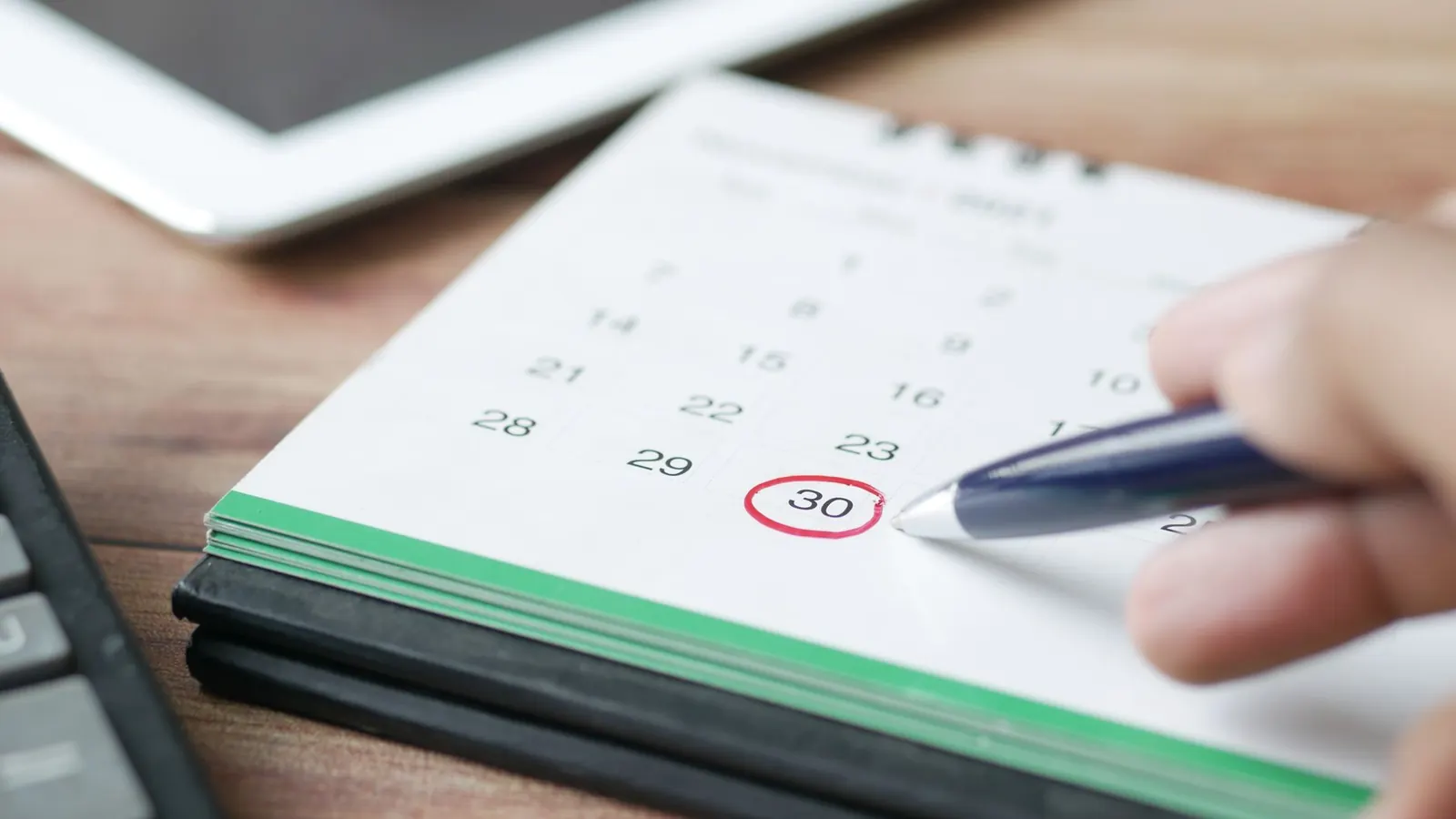 A hand circling a date on a calendar with a pen, representing the timeline of a private investigation from consultation to final report