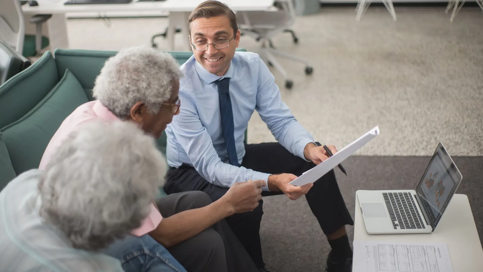 An advisor showing a document to two clients during a consultation, representing the questions worth asking before hiring a private investigator