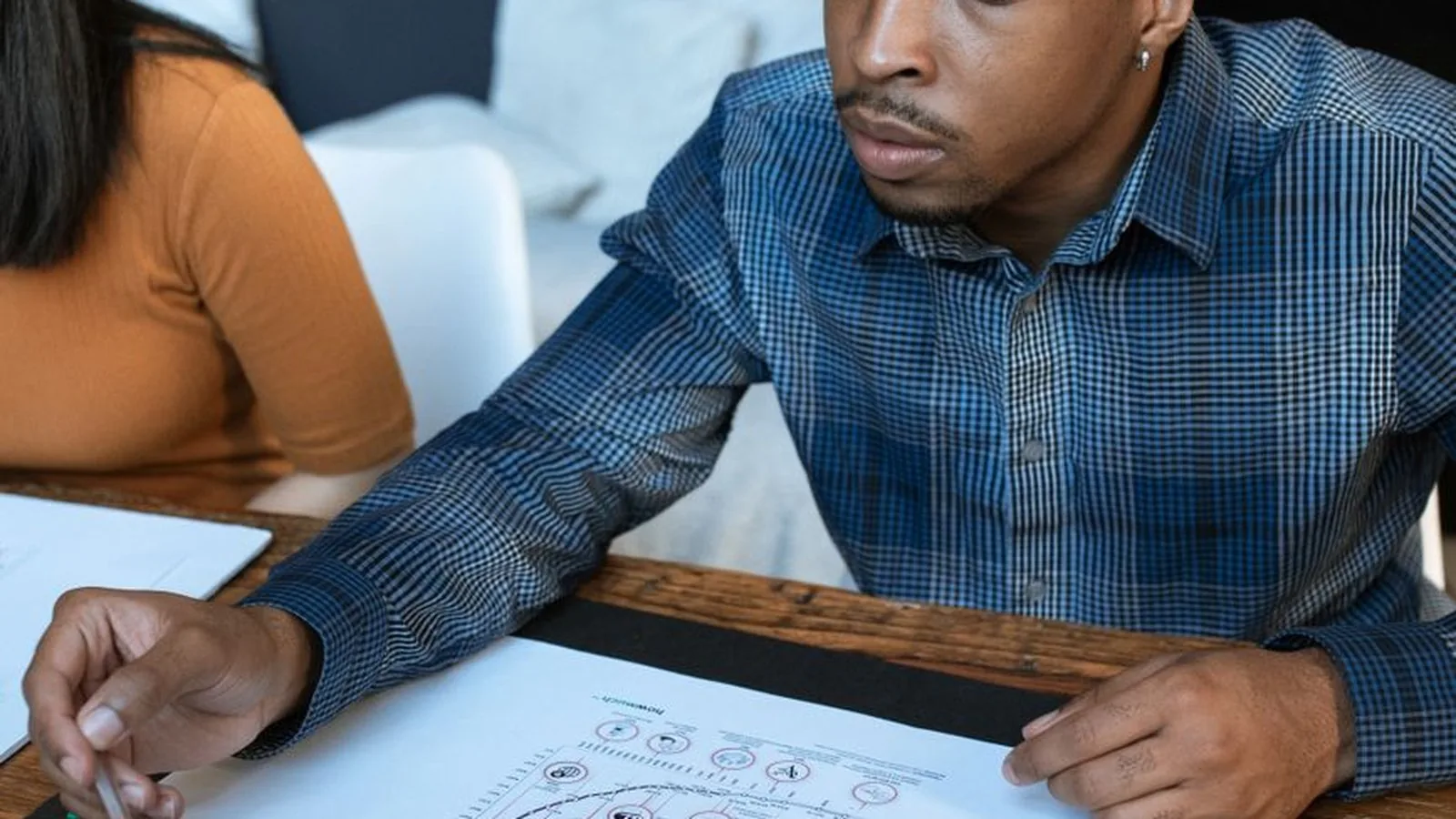 A man closely examining a printed report with charts, representing a corporate or internal fraud investigation