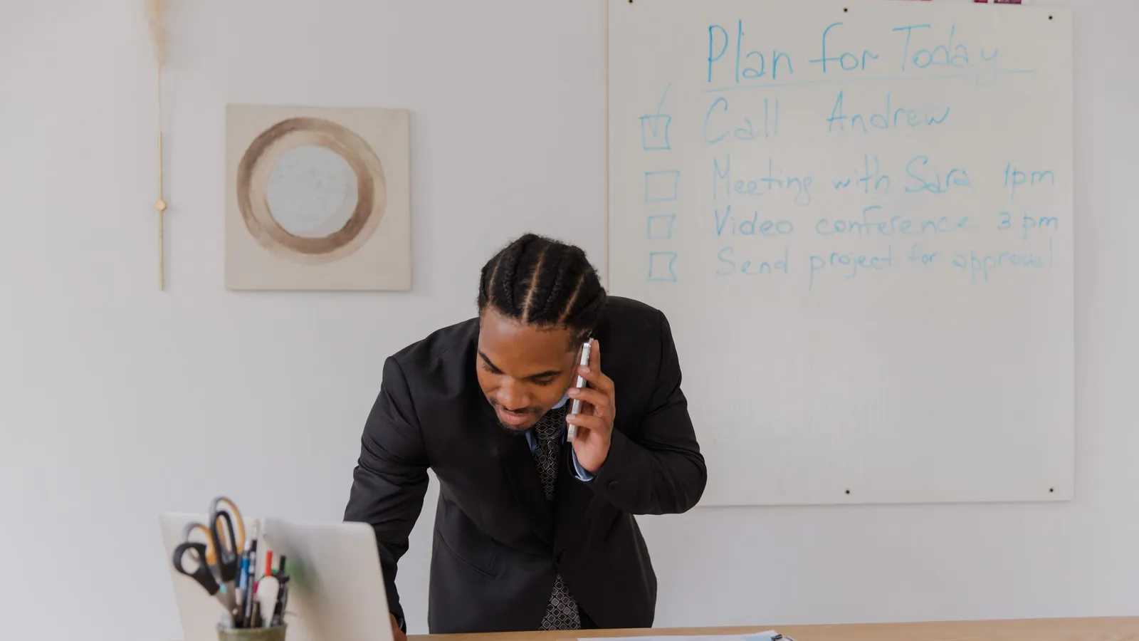 A man on the phone at a whiteboard covered in notes, representing the communication expectations worth setting upfront with a firm