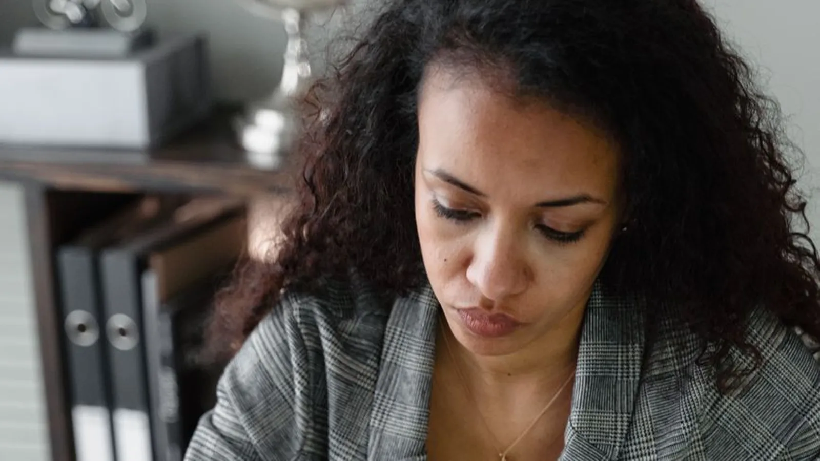 A woman using a calculator with cash and a laptop on her desk, representing the cost and payment questions worth clarifying before committing
