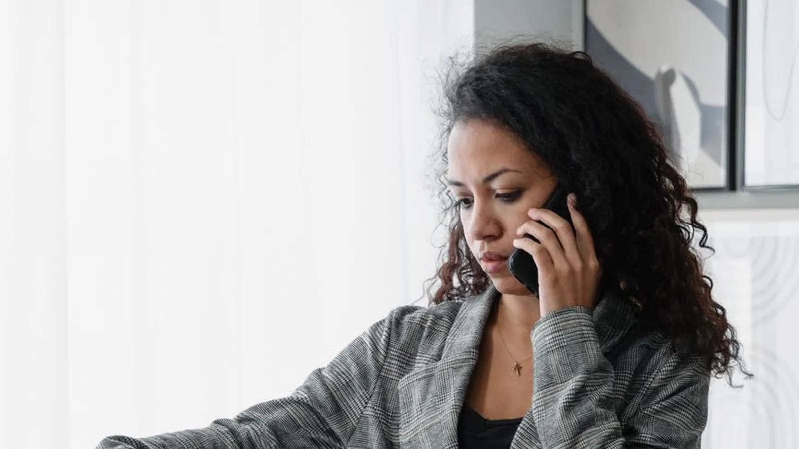 A woman on the phone reviewing documents at her desk, representing a policyholder gathering independent facts to support a disputed insurance claim