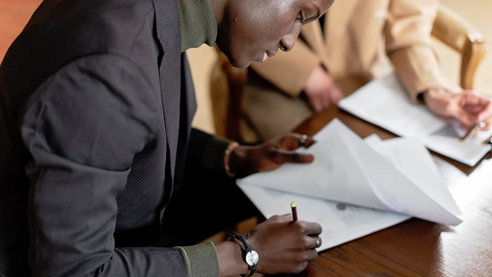 Two colleagues reviewing paperwork together at a desk, representing the verification work behind vetting a new hire or business partner