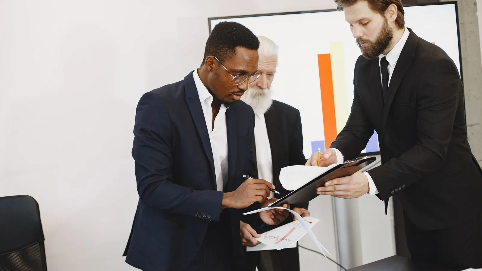Two businessmen reviewing a document together in a boardroom, representing due diligence carried out before a deal is signed