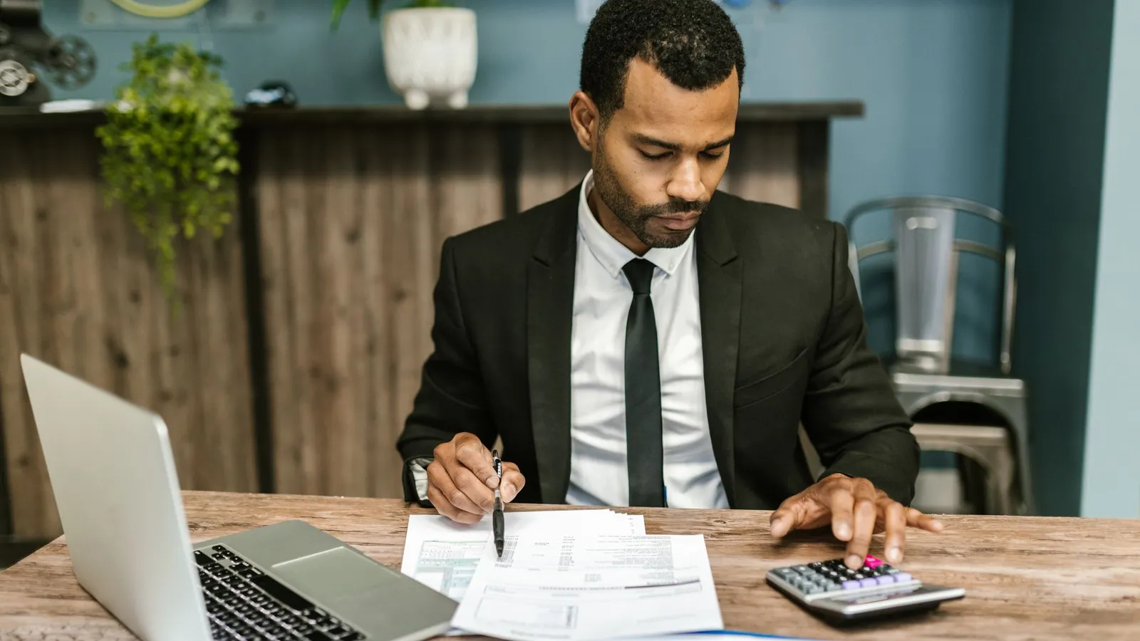 A businessman working through financial documents and a calculator at a desk, representing the math behind investigation as a return on investment