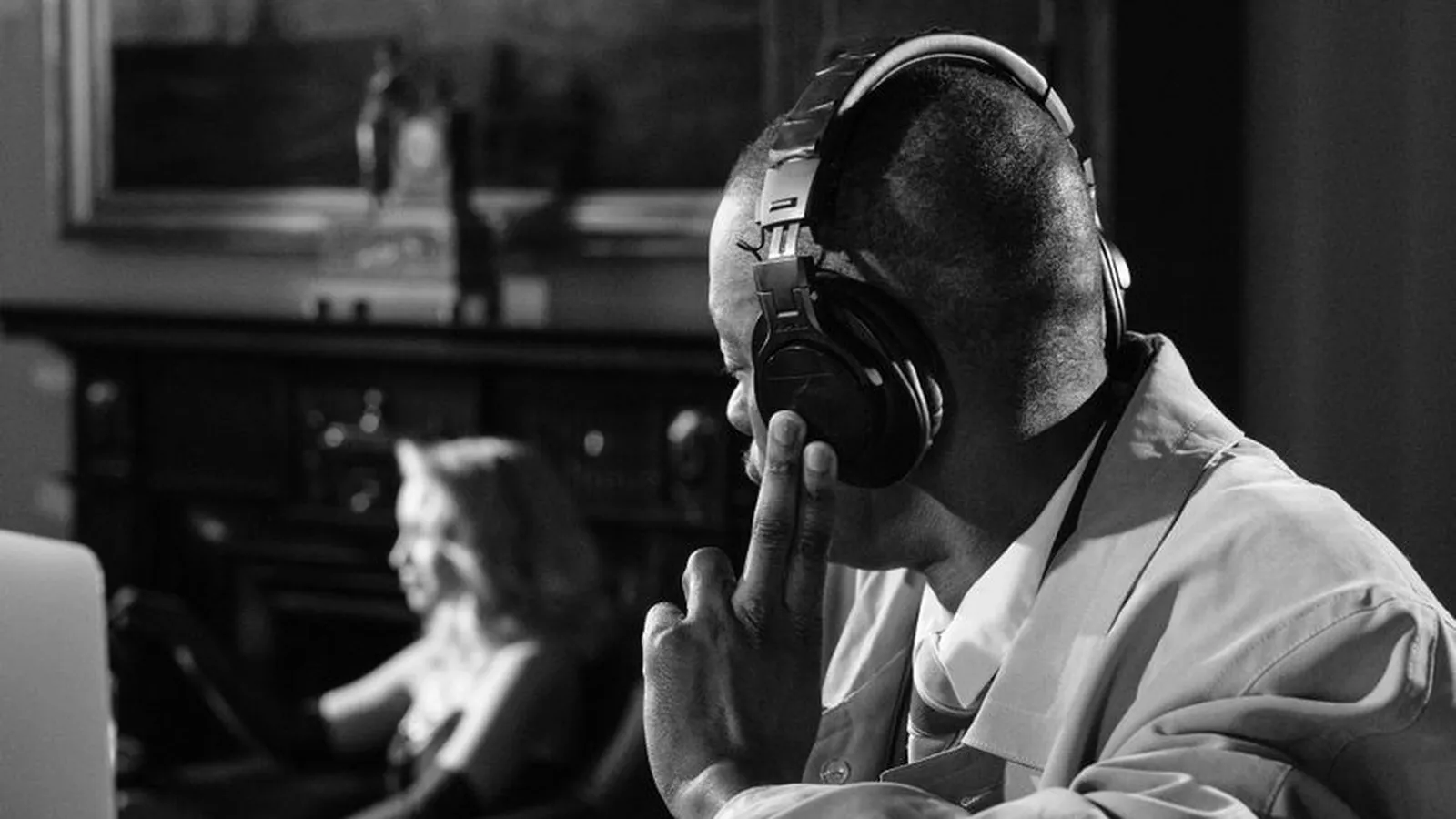 An investigator wearing a hat and headphones working at a laptop in low light, representing the tracing work behind locating a debtor or missing partner