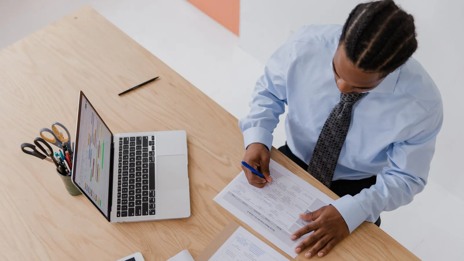 A man alone at his desk signing a document with no one else present, representing a process with a single point of control and no second check