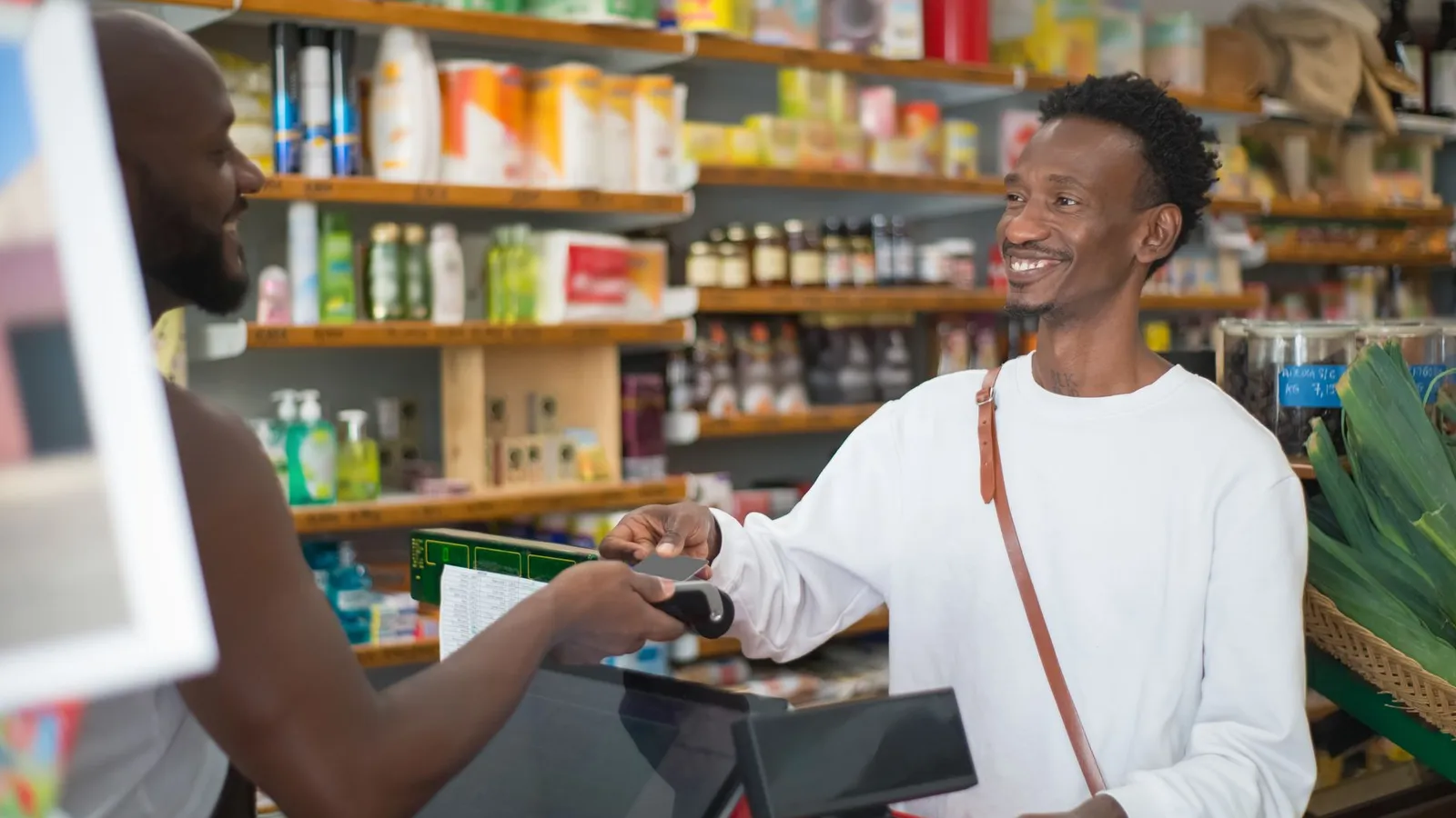 A customer handing something to a shopkeeper at the counter, representing the outside interactions that sometimes reveal a pattern before the business owner notices it