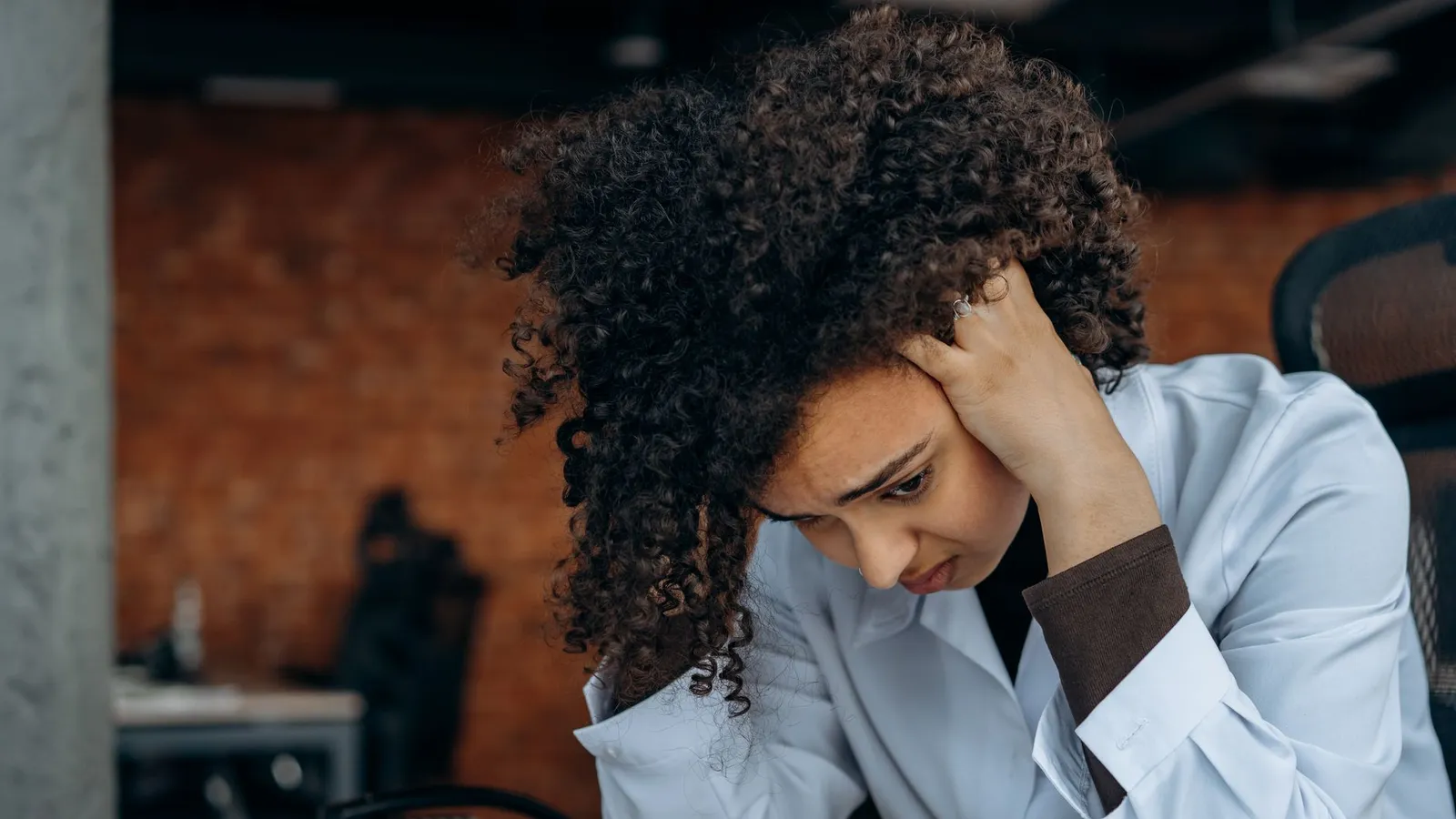 A businesswoman sitting at her desk with her head in her hand, looking worried, representing the gut feeling that something is off before it's confirmed