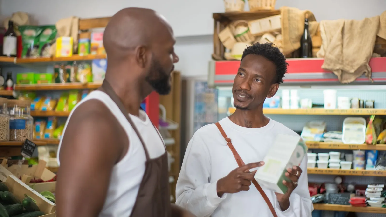 Two men in a shop with one holding a product, representing the physical stock check that eventually surfaces a discrepancy the books alone can't show