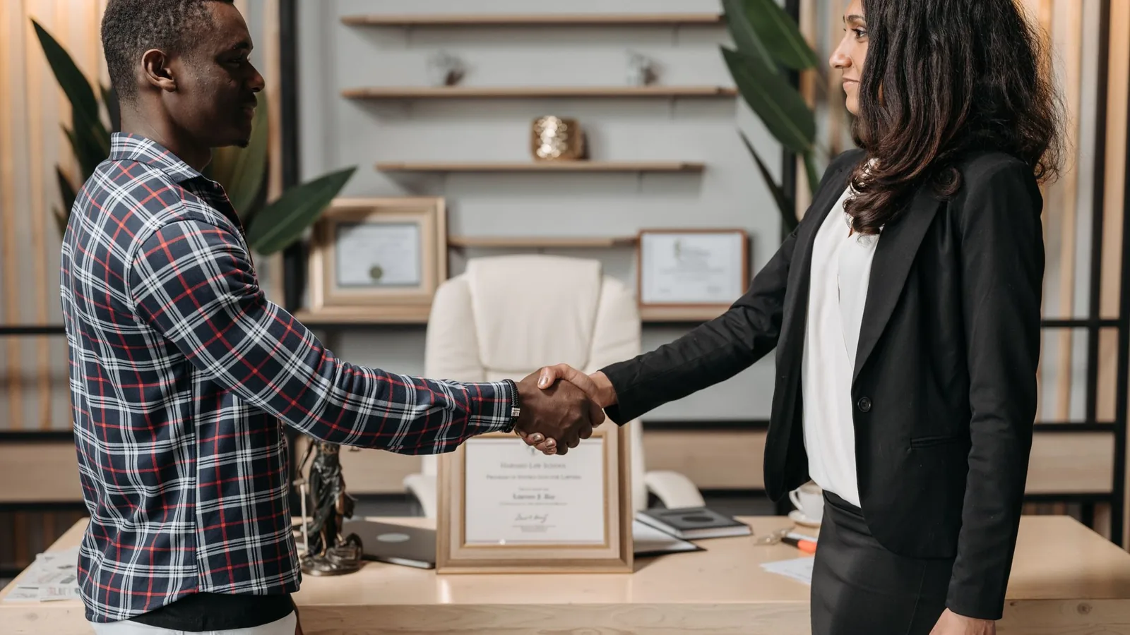 Two people shaking hands in an office, representing a private investigator being engaged by a private client