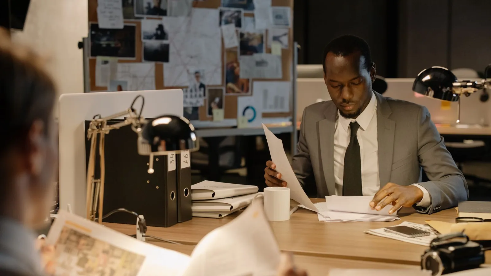 A man in a suit reviewing documents in front of an evidence board, representing the range of case types a private investigator typically handles